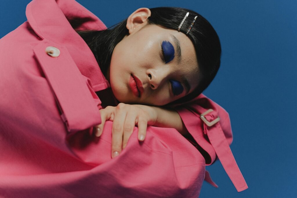 Girl wearing pink jacket with blue eye makeup and red lipstick